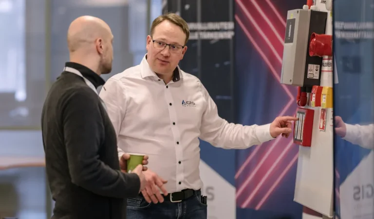 Agiksen edustaja esittelee yrityksen edustamaa paloturvateknologiaa messujen esittelyosastolla.